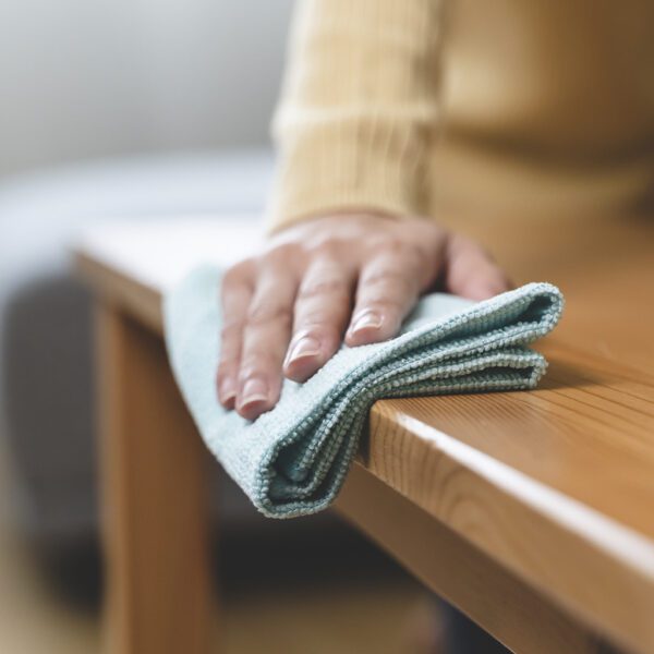 A woman wiping a Microfibre Clene - Large Micro-Fibre Cloth - x1 LMF001 on a wooden table.