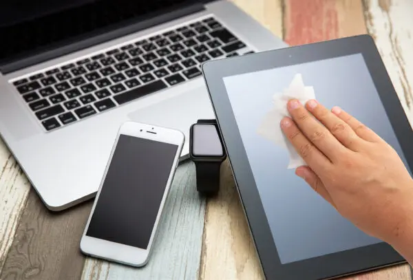 Eine Hand wischt ein Tablet mit einem Screen-Clene - Individual Screen Cleaning Wipe ab.