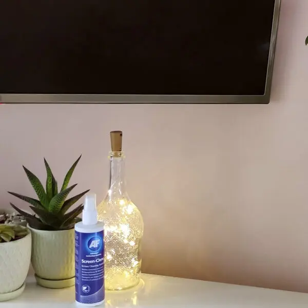 Eine Flasche Screen-Clene – Universal Screen Cleaning Pump Spray – 250 ml SCS250 auf einem Tisch neben einem Fernseher.