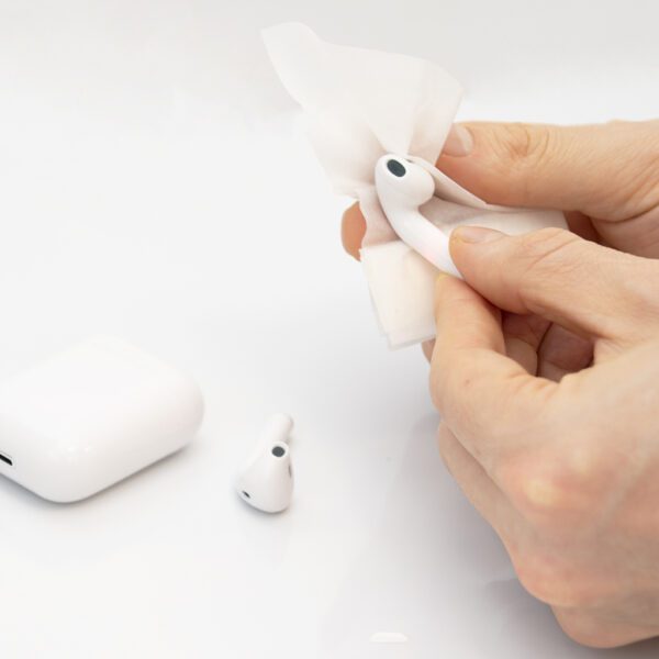 Cleaning white wireless earbuds with tissue paper.