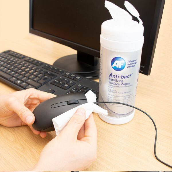 Hand cleaning computer mouse with wipes.