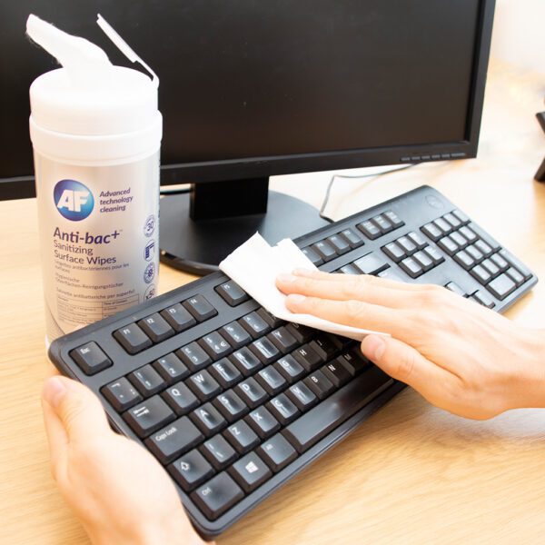 Hand cleaning computer keyboard with wipe.