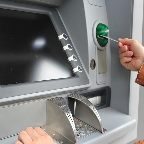 Une personne mettant de l'argent dans un Cardclene - Cartes de nettoyage à tête magnétique et à puce ATM - x20 CCE020C.