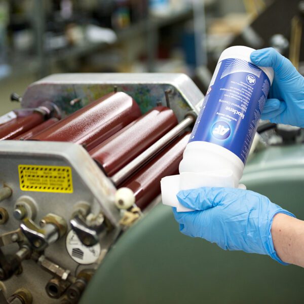 Eine Person hält eine Flasche Isoclene – 99.7 % reine Isopropyl-Reinigungslösung – 250 ml ISO250 auf einer Maschine.