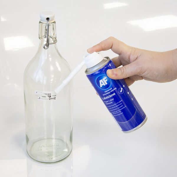 Eine Person verwendet Label Clene – Papieretiketten-Aufkleberentferner mit Pinsel – 200 ml LCL200, um eine Glasflasche zu reinigen.