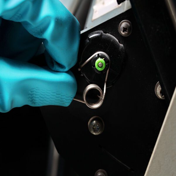 A person in a blue glove is putting a Platenclene - Printer Roller Cleaner/Restorer - 100ml Spray PCL100 into a car door.