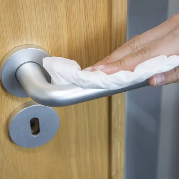 Une personne essuyant une poignée de porte avec des chiffons de nettoyage non tissés Safecloths - x50 SCH050.