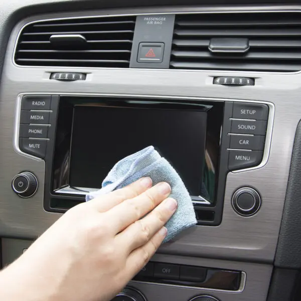 Eine Person, die den Multi-Screen Clene – Sanfte Bildschirmreinigungslösung und großes Mikrofasertuch – 200 ml MCA_200LMF in einem Auto reinigt.
